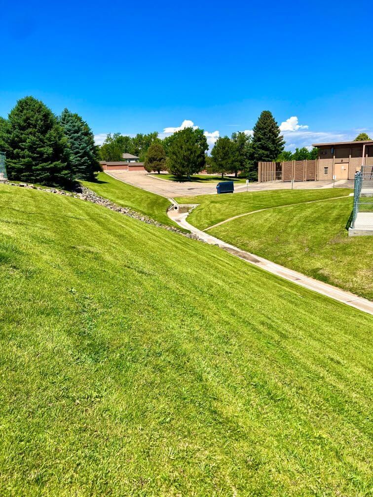 trimmed grass and trees on a hill to a drain ditch at a business