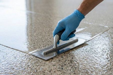 A close-up of a Gateway Concrete Coating technician applying the final topcoat to a garage floor with precision.