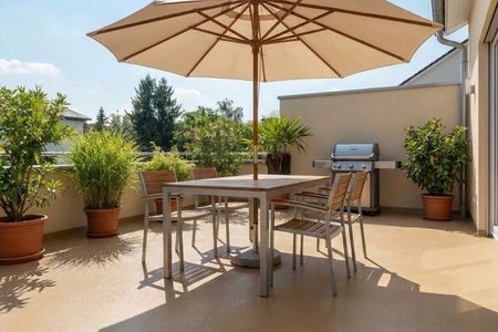 A sun-drenched outdoor patio with a tan epoxy floor coating, furnished with a dining set and a large umbrella.