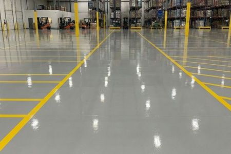 A large commercial warehouse floor with a durable, high-gloss epoxy coating and yellow safety lines.