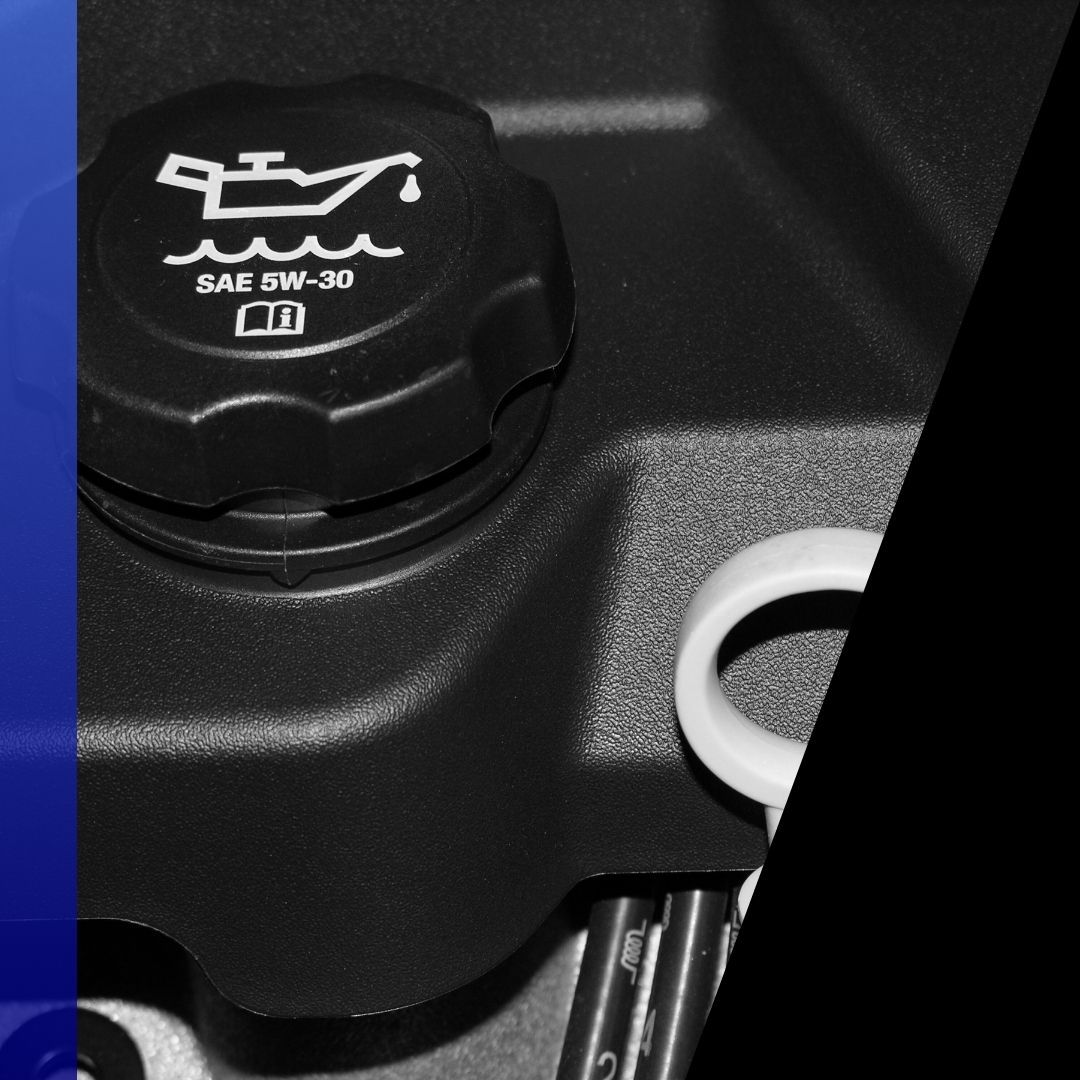 xtreme close-up of a black oil filler cap marked SAE 5W-30 and a white dipstick guide tube on a vehicle engine.