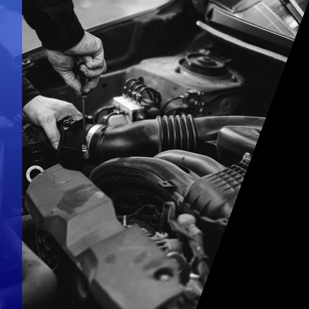 Close-up shot of a mechanic's hands working on the engine components of a standard passenger vehicle, representing general auto maintenance.