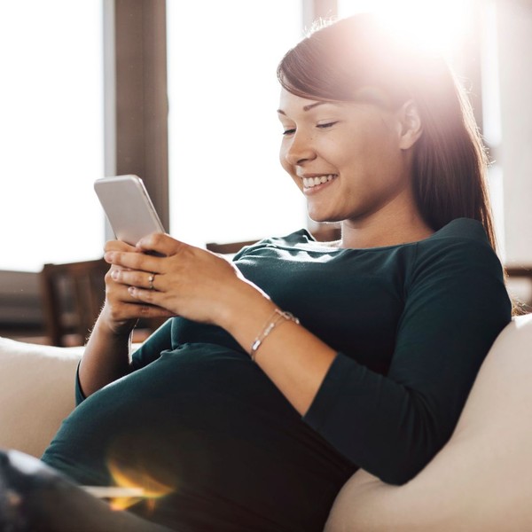 Pregnant woman smiling at her phone