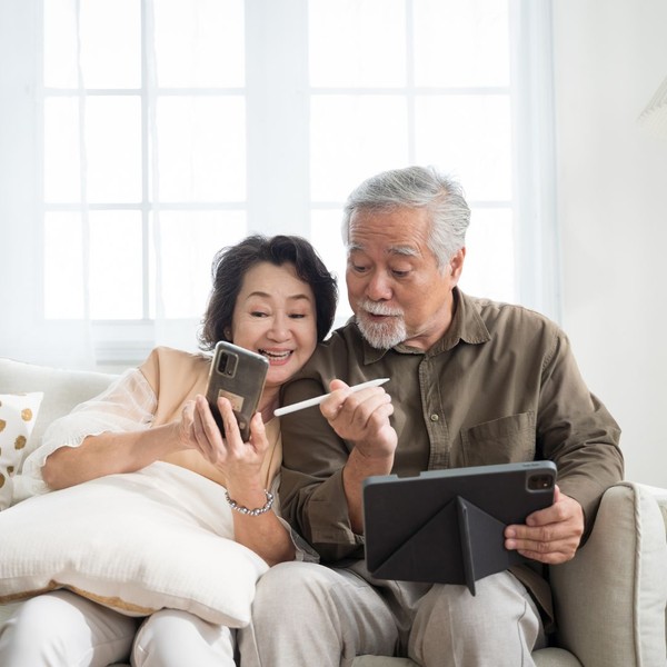 couple happily using an ipad and phone together