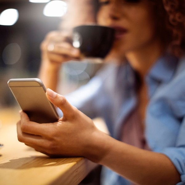 woman sipping coffee while using her phone