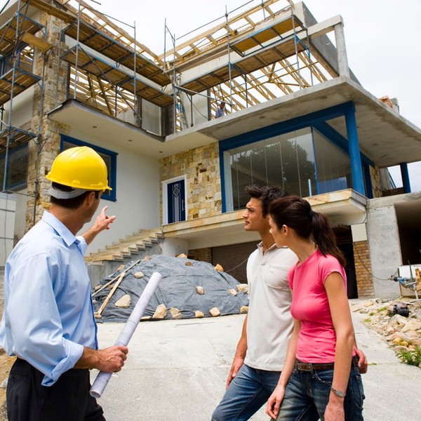 Contractor pointing to house under construction with couple