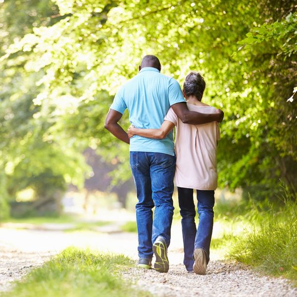 Older man and woman holding each other as they walk