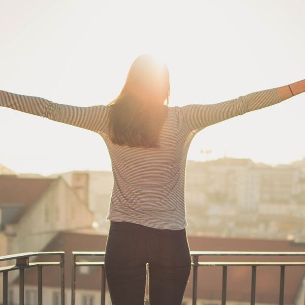 Woman with arms outstretched facing the sunlight