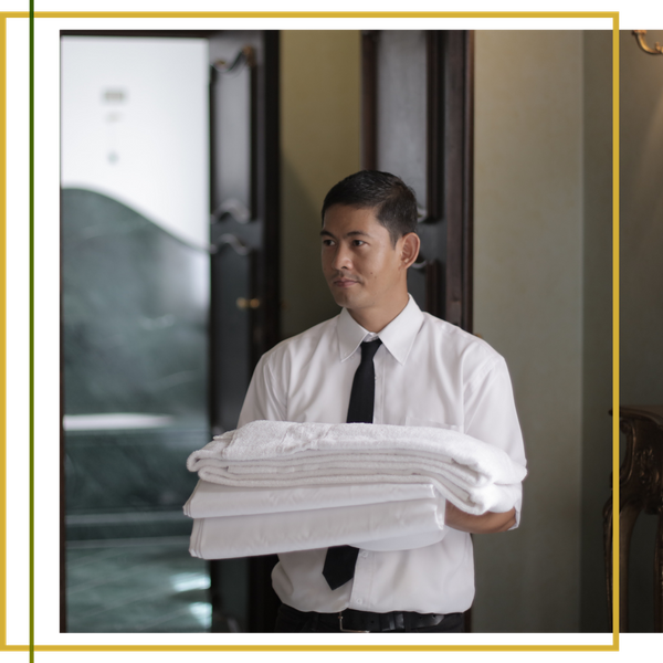 hotel staff member holding stack of folded white linens