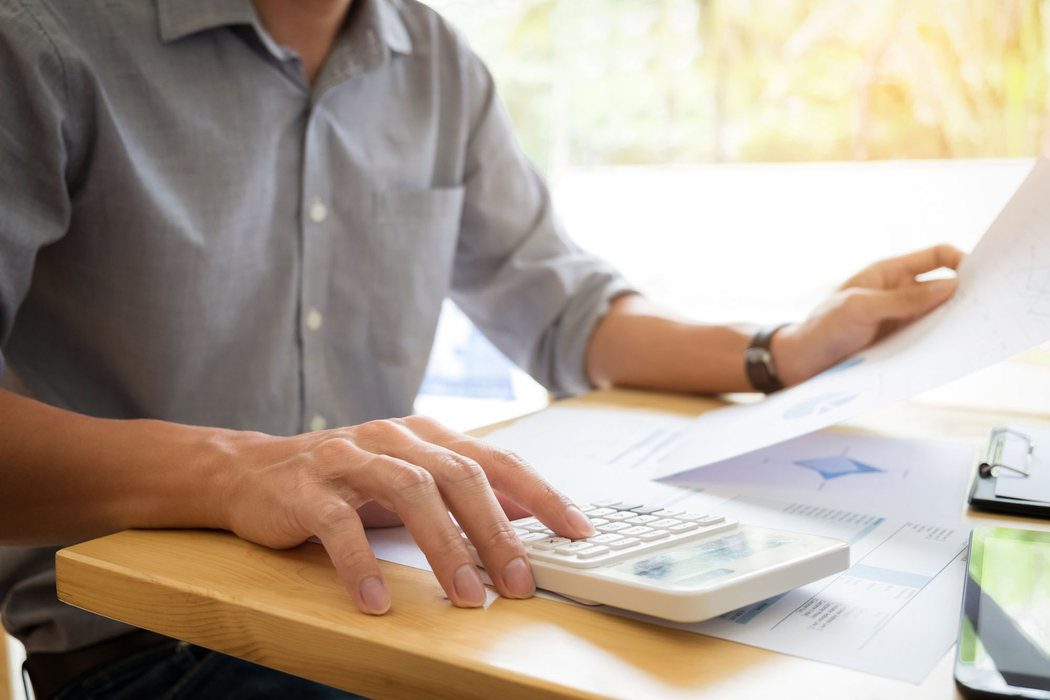 A close-up shot of a stack of documents with a pen and a calculator on top A close-up shot of a stack of documents with a pen and a calculator on top
