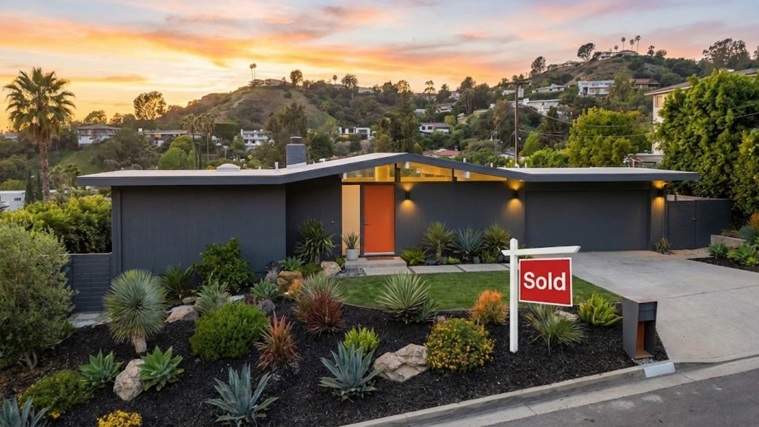 A stylish mid-century modern home in a hilly Los Angeles neighborhood at sunset with a "Sold" sign in the front yard