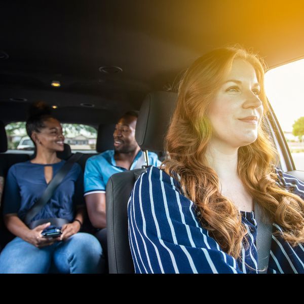 a woman driving with people smiling in the back