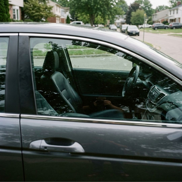 A view through a car window showing an empty driver's seat.