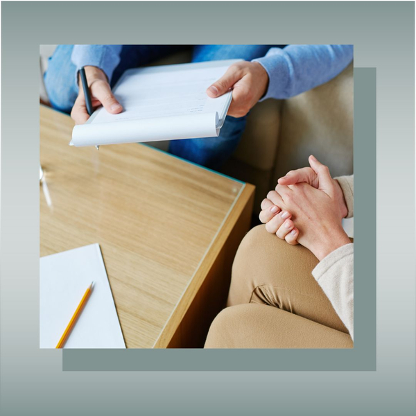 Person holding paperwork while other waits with clasped hands