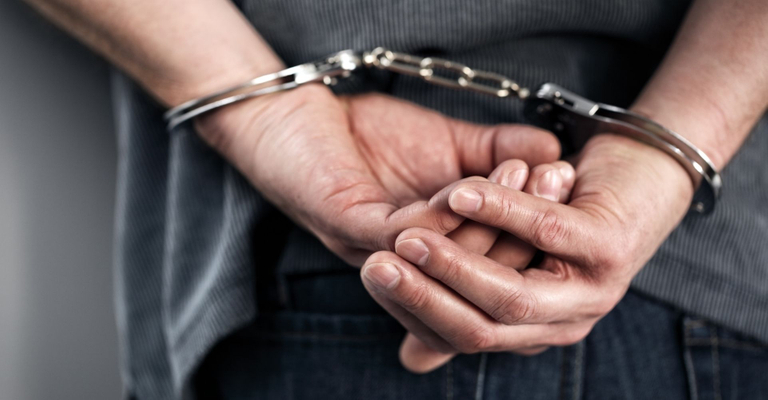 Man standing with his hands in handcuffs behind his back. Man standing with his hands in handcuffs behind his back.