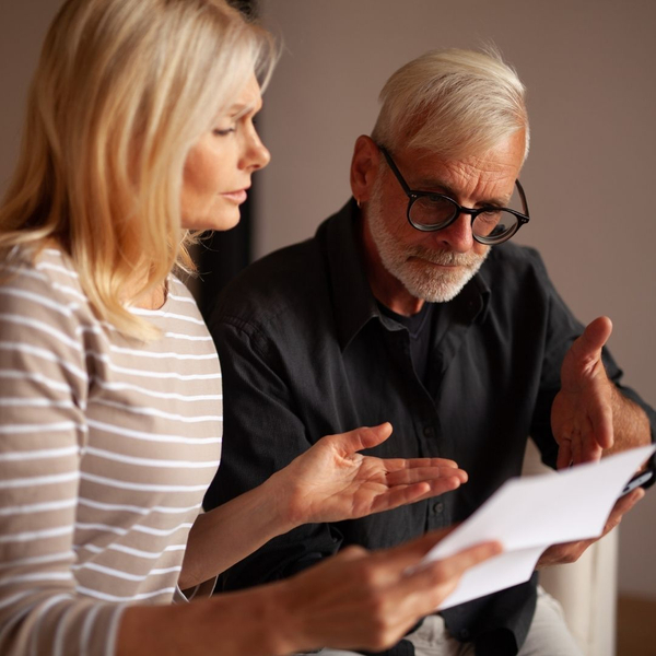 An older man and woman look concerned while reviewing a legal paper together.