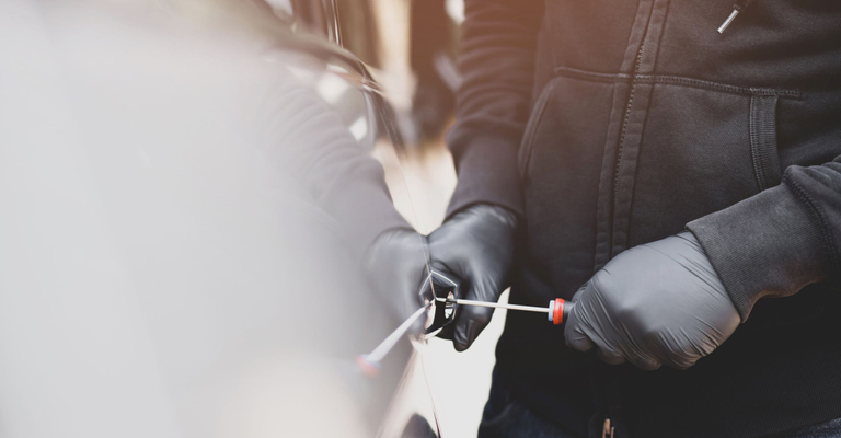A person breaking into a car.