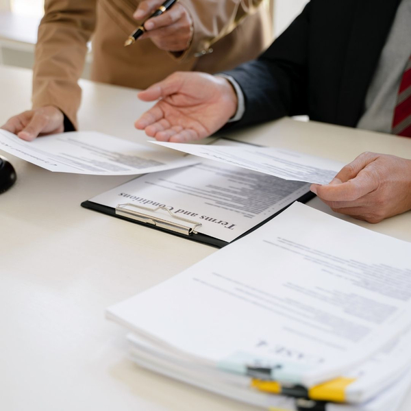 Two attorneys review legal documents, with a clipboard showing "Terms and Conditions."
