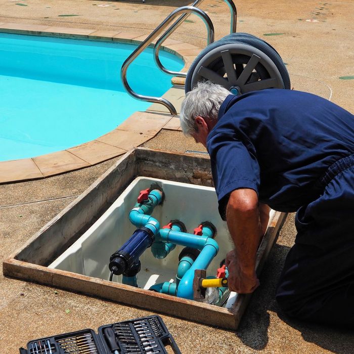 a person inspecting pool pipes