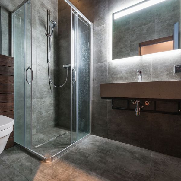 intense slate, glass, and dark brown bathroom with lighted mirror