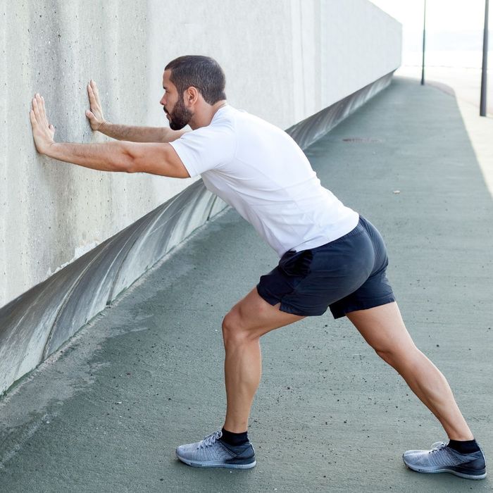 man stretching against wall