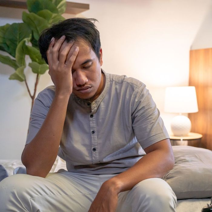 a man holding his head tired in bed