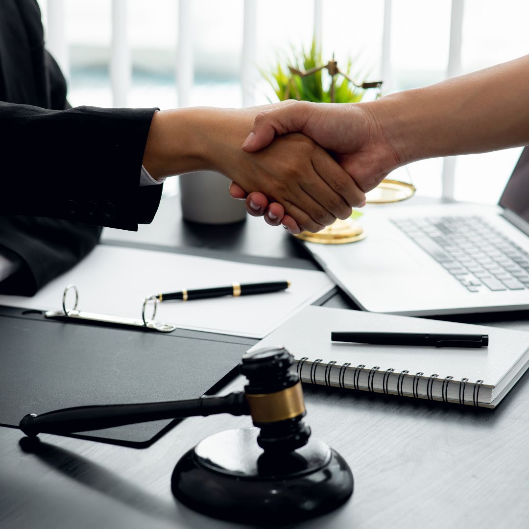 people shaking hands over paperwork and a gavel