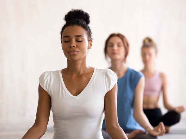 A group of beautiful women sitting in a lotus position meditating during a session at a yoga studio. 