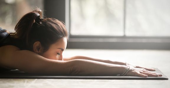 Woman stretching out on her yoga mat with eyes closed