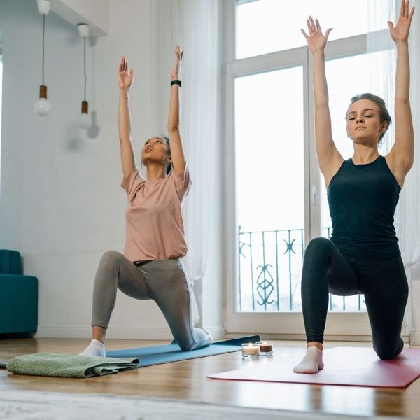 two woman doing yoga in a house