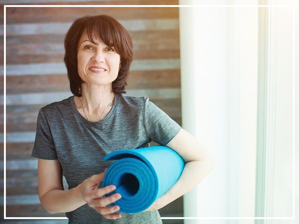 photo of woman holding blue yoga mat