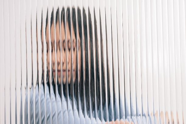 Girl sitting behind distorted mirror