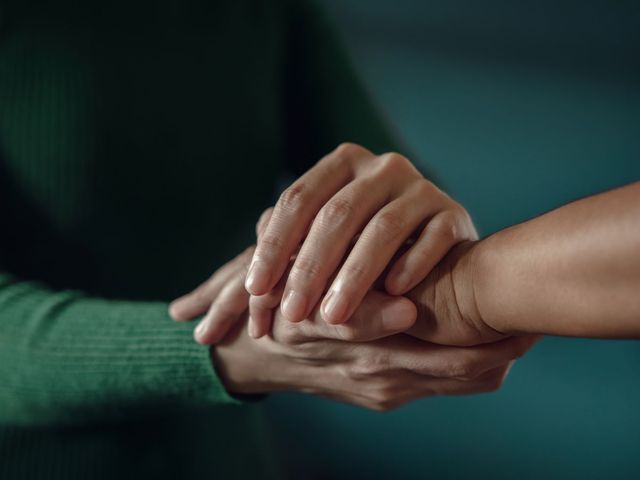 woman holding a hand in a supportive/consoling manner
