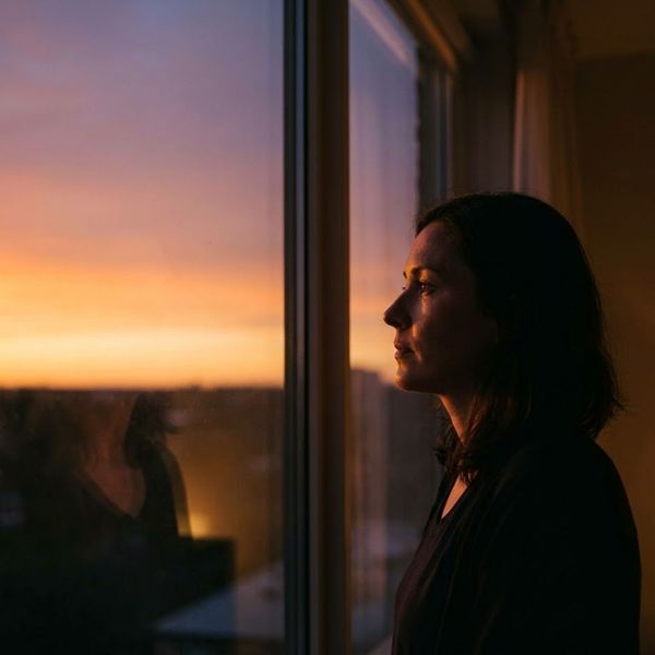  A woman looking out the window at a sunset.