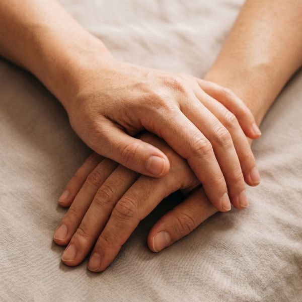 Two people holding hands in comfort.