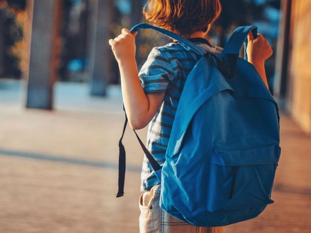 child with backpack in front of school building