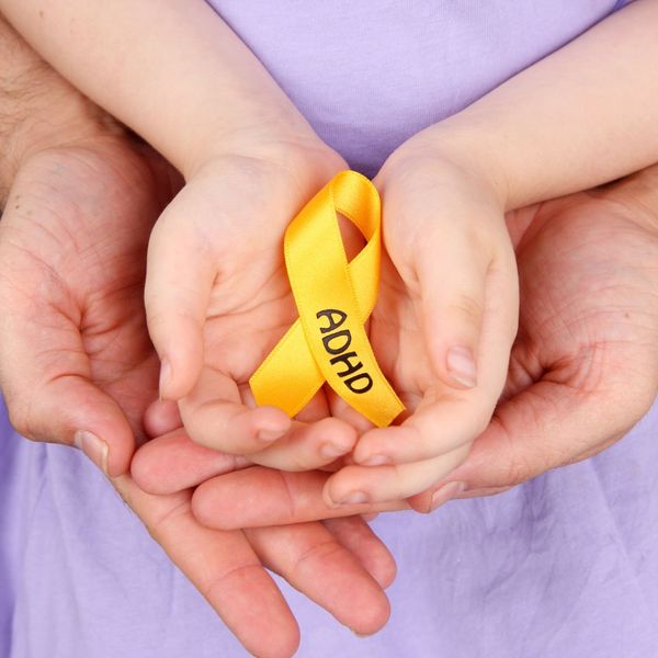adult and kid's hands holding ADHDH ribbon