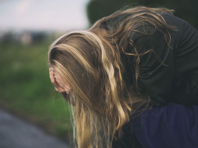 young woman bent over with her head in her hands in depression