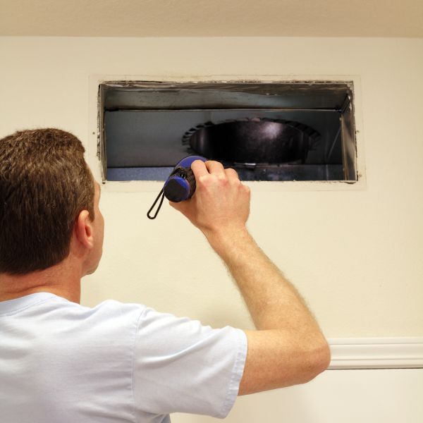 person checking air duct with flashlight