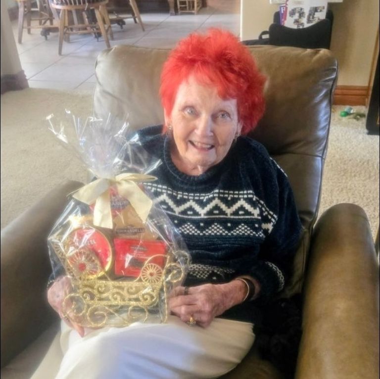 A senior woman with bright red hair smiling while holding a gift Personal Care