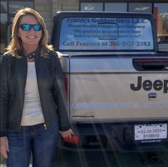 A woman smiling and standing by a truck with a branded Frank's Golden Girls window wrap Errands