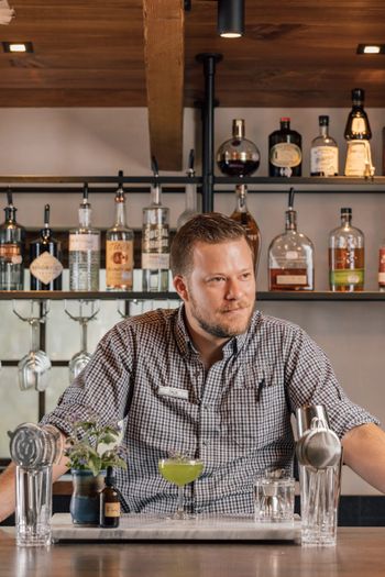 A bartender with a freshly crafted cocktail in front of him at the bar 2021-11-04 BLOG The Swag - The Garden Gnome Cocktail - Waynesville, NC - Jack Robert Photography23