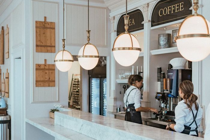 A luxury coffee and tea bar with pendant lighting hanging over the marble counters