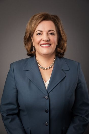 Smiling woman with suit jacket and pearl necklace