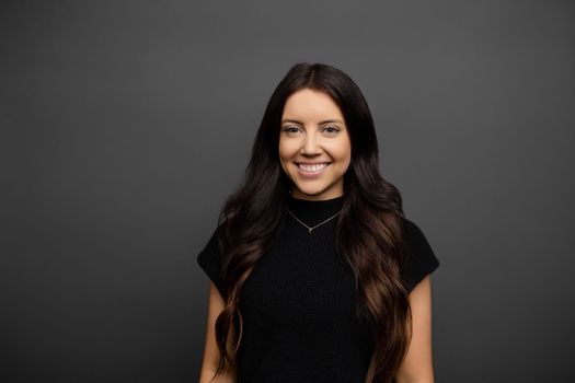 Smiling woman with black short sleeve blouse and dainty necklace