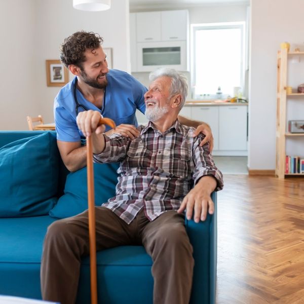 caretaker helping elderly man in a home
