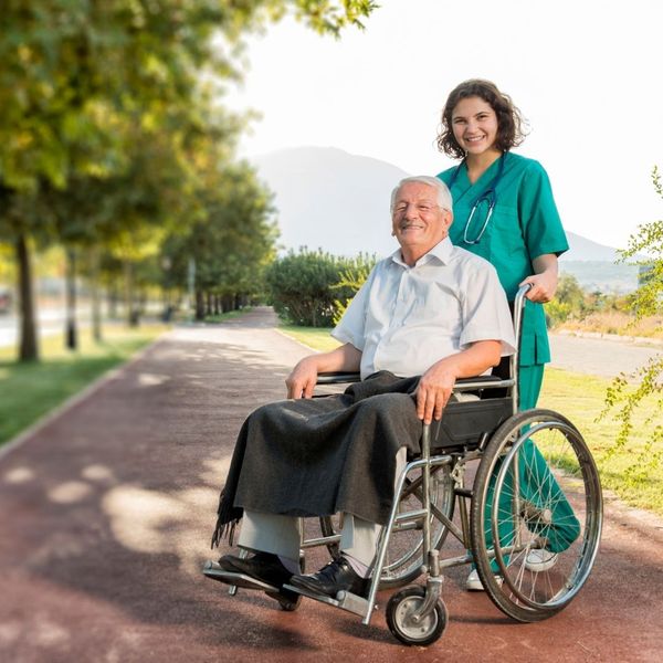 Caretaker helping elderly man in wheelchair