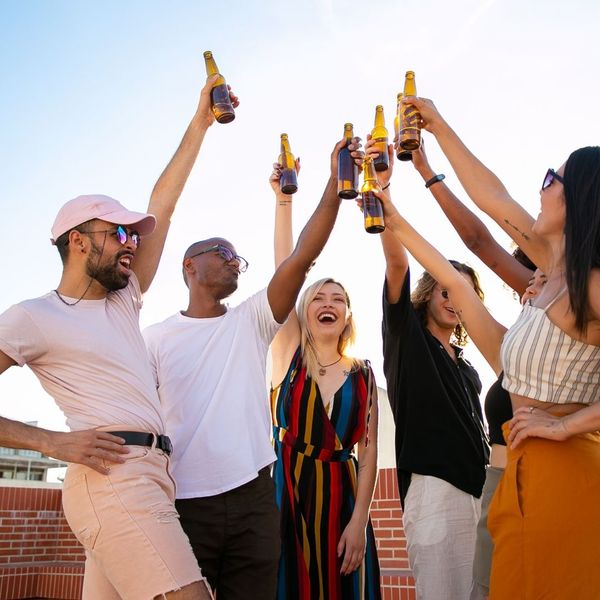 group of friends holding up beer bottles to cheers at event