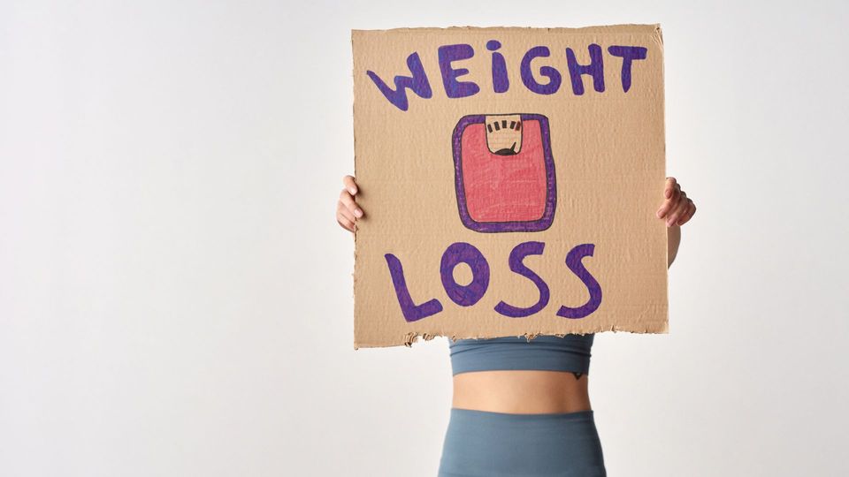 Woman holding a cardboard sign that says "Weight Loss".