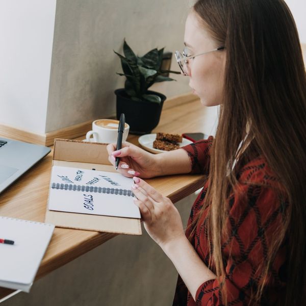 Woman writing goals in a notebook. 